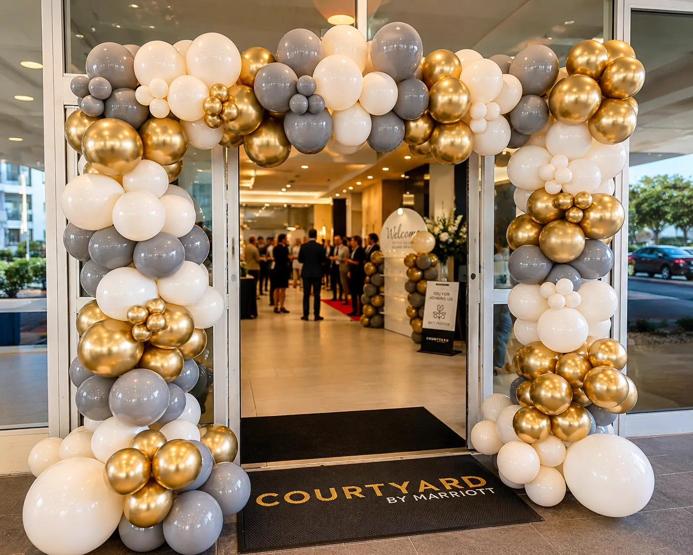 Gold, white and grey balloon arch styled in a hotel event lobby