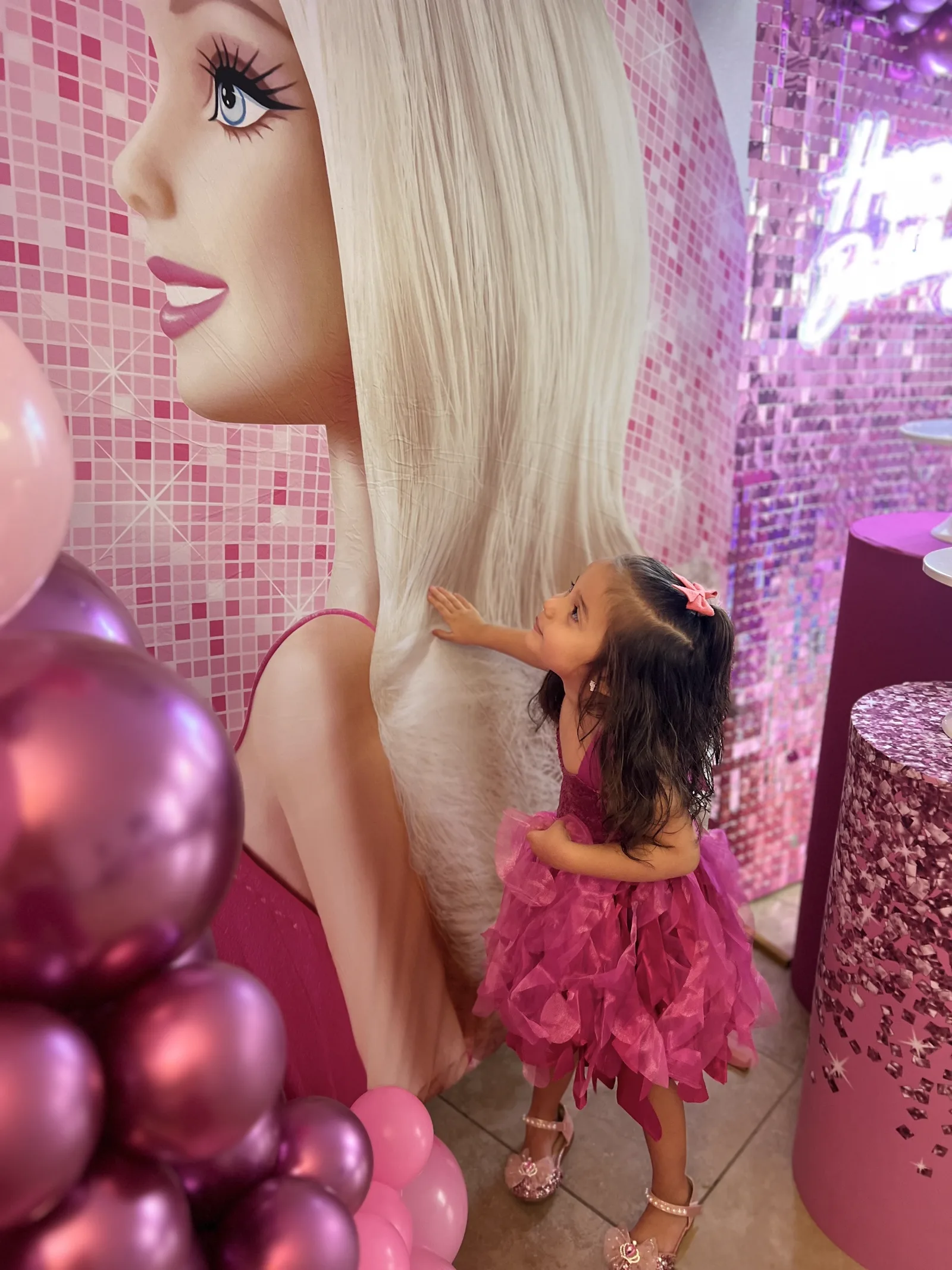 Child posing with a pink balloon installation at a themed kids party