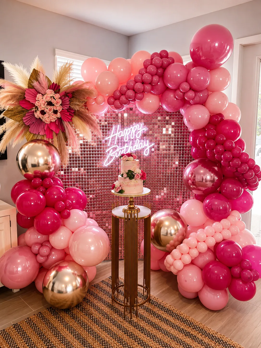 Pink and gold balloon arch around a shimmer wall birthday cake table